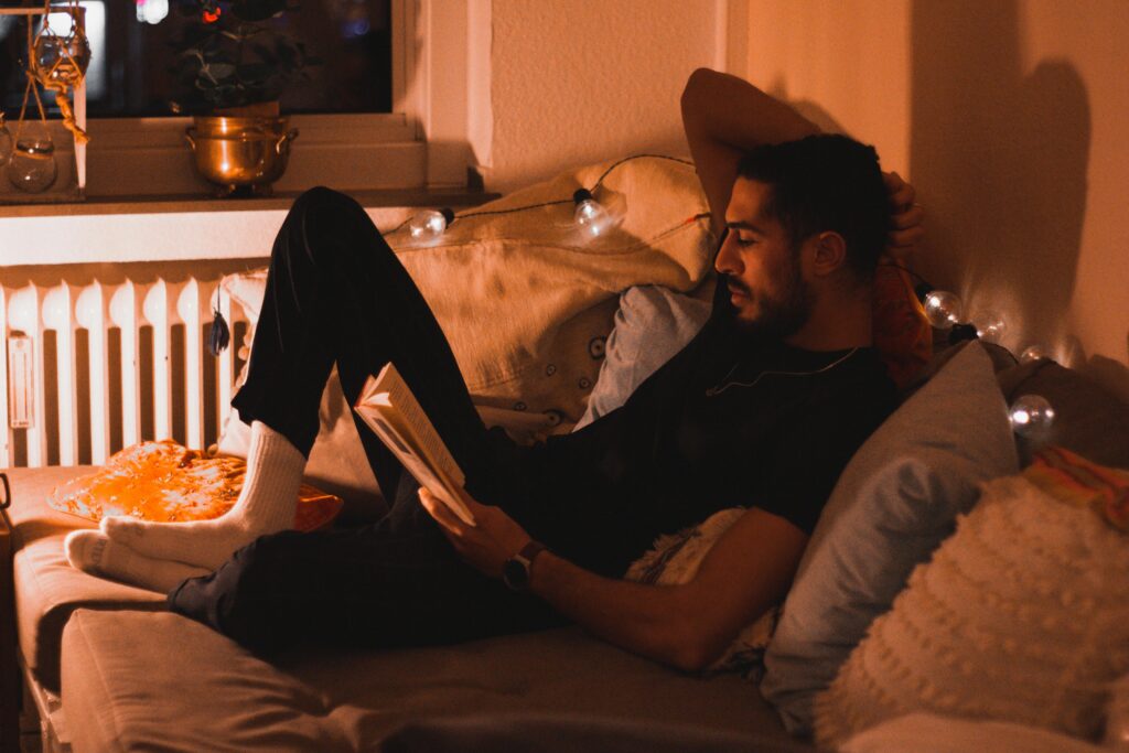 Person enjoying a peaceful moment reading a book in a cozy environment.