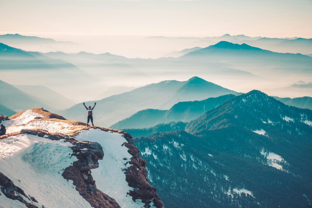 Man standing triumphantly on mountain representing the achievement and freedom that comes from building self-discipline5