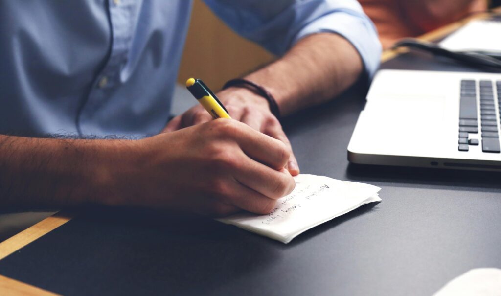 Person writing in a journal notebook to empty thoughts and stop overthinking